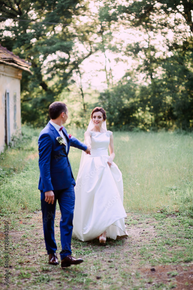 beautiful and young groom and bride walking together outdoors