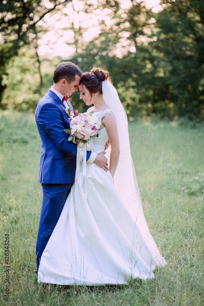 beautiful and young groom and bride standing together outdoors