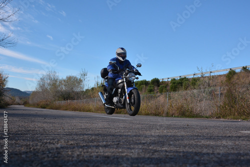 biker with helmet blue going by a road