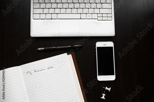 White laptop with laptop and phone on a black background for business and work
