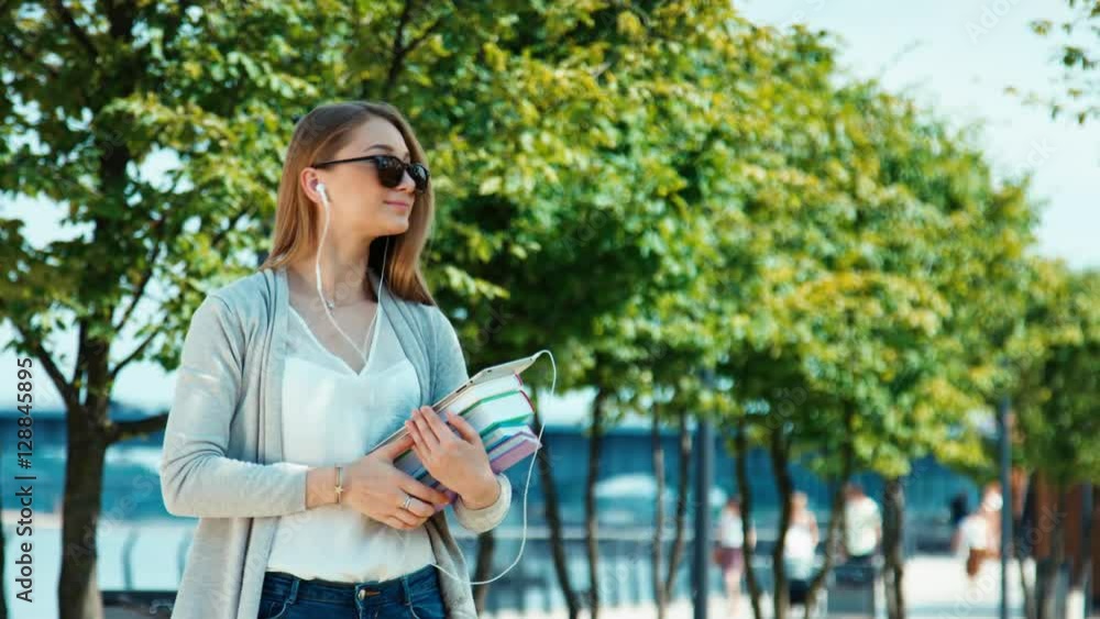 Young student girl standing in the city quay holding her books and tablet pc and smiling at camera Young student girl standing in the city quay holding her books and tablet pc and smiling at camera