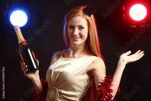 Happy red-haired girl with a bottle of champagne in their hands, having fun at a party. © Studio KIVI