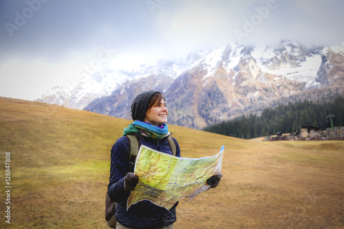 Young woman traveler with a backpack and a map on the background photo