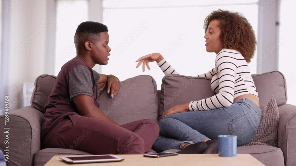 African American man and woman talk while relaxing on their couch in their living room African American man and woman talk while relaxing on their couch in their living room