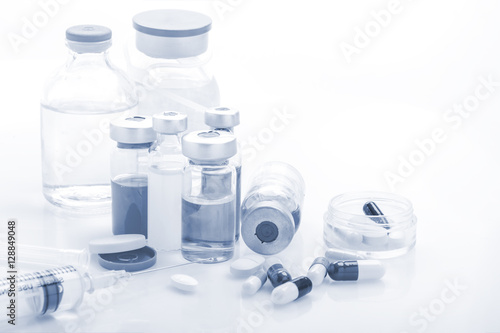 Fototapeta Naklejka Na Ścianę i Meble -  Glass Medicine Vials with syringe pills capsule on white table