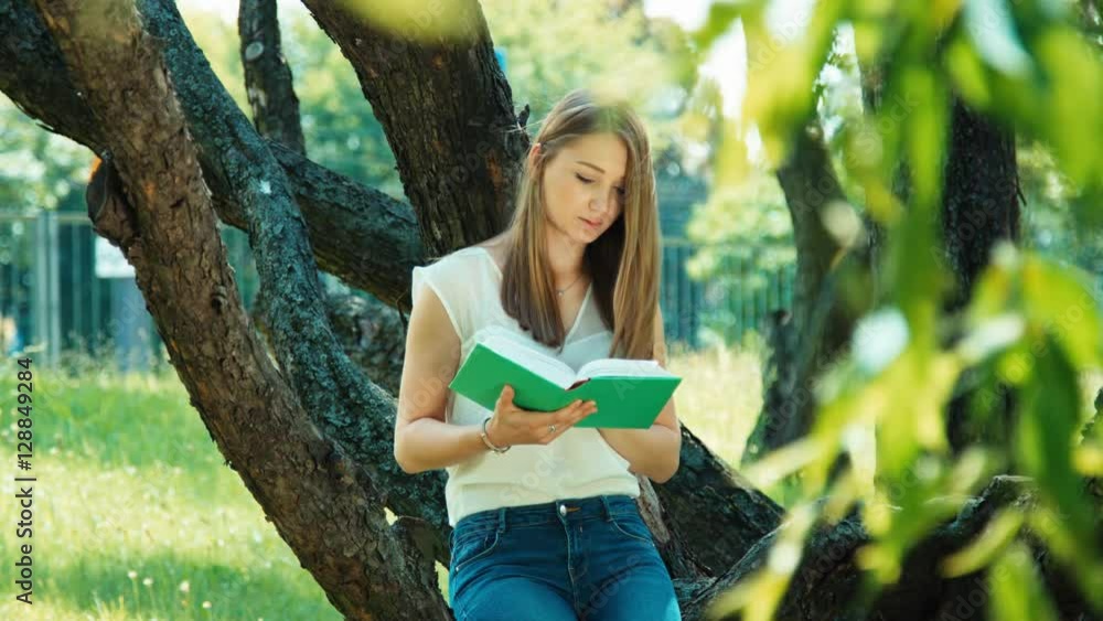 Young student reading book outdoors and looking at camera with smile Young student reading book outdoors and looking at camera with smile