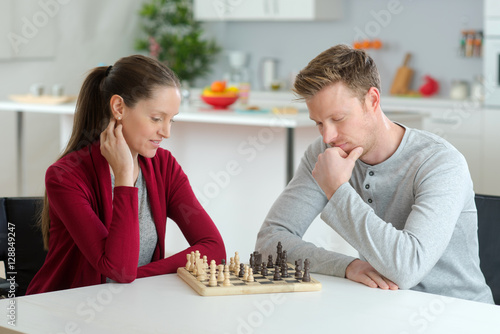 happy young couple playing chess in living room