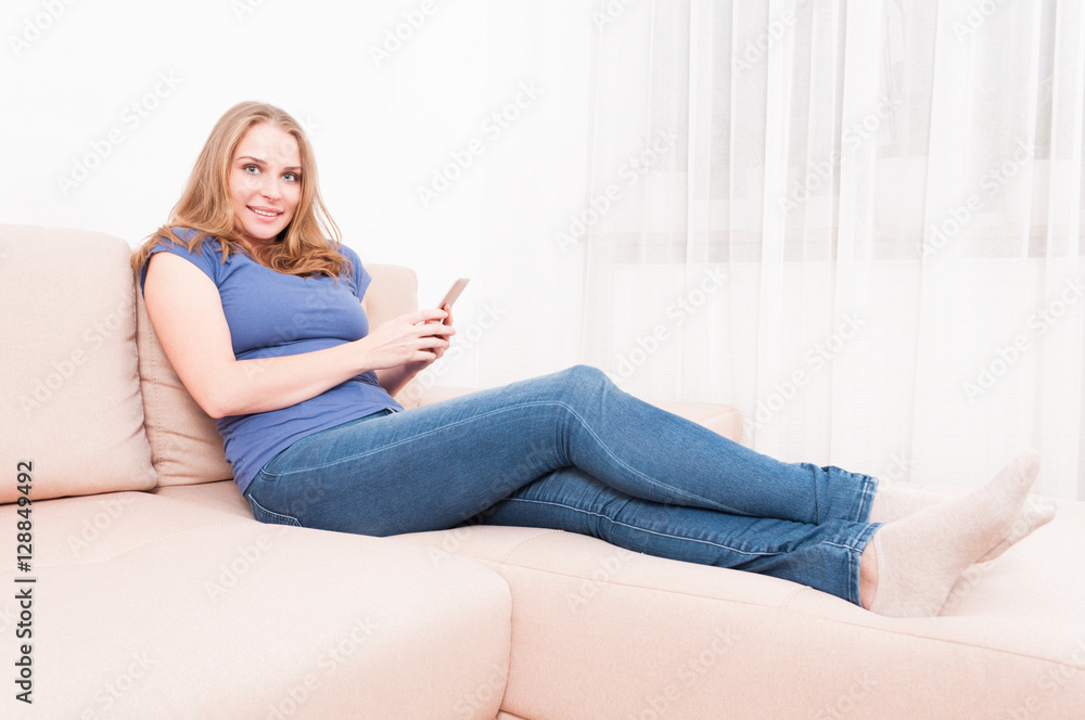 Pretty lady sitting on couch holding smartphone Pretty lady sitting on couch holding smartphone