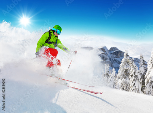 Freeride skier on piste running downhill