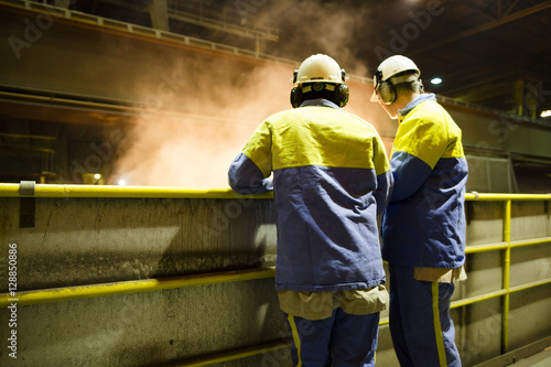 workers of a steel factory look at the manufacturing process