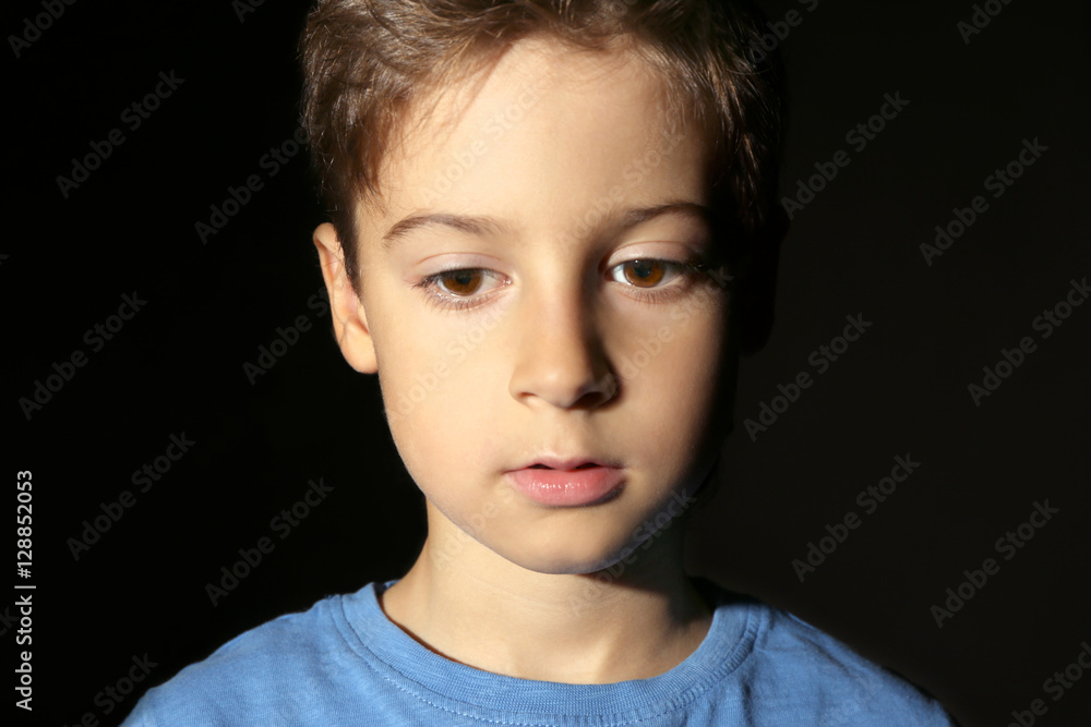 Cute little boy on black background, close up view