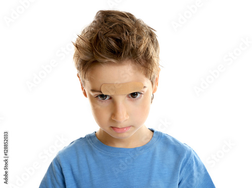Cute little boy with plaster applied onto forehead, on white background