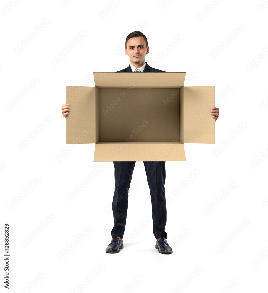 Businessman standing and holding big open empty light beige cardboard mail box in his hands, isolated on the white background.