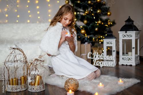 A gial in front of the fir tree with a gift and candles photo