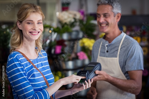Smiling woman making payment with her credit card to florist