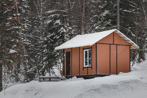 a small wooden house of tourist shelter or hostel in a snowy forest