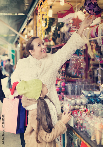 woman with daughter buying gifts at Christmas market