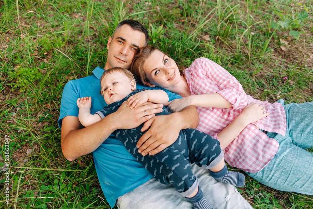 happy family in the park lying on the grass in the summer happy family in the park lying on the grass in the summer