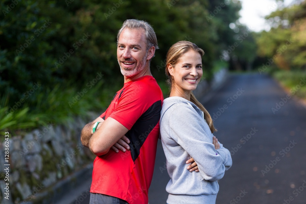 Obraz premium Athletic couple standing back to back on the open road