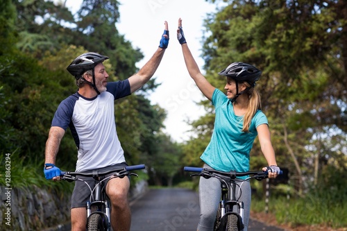 Athletic couple giving high five while riding bicycle 
