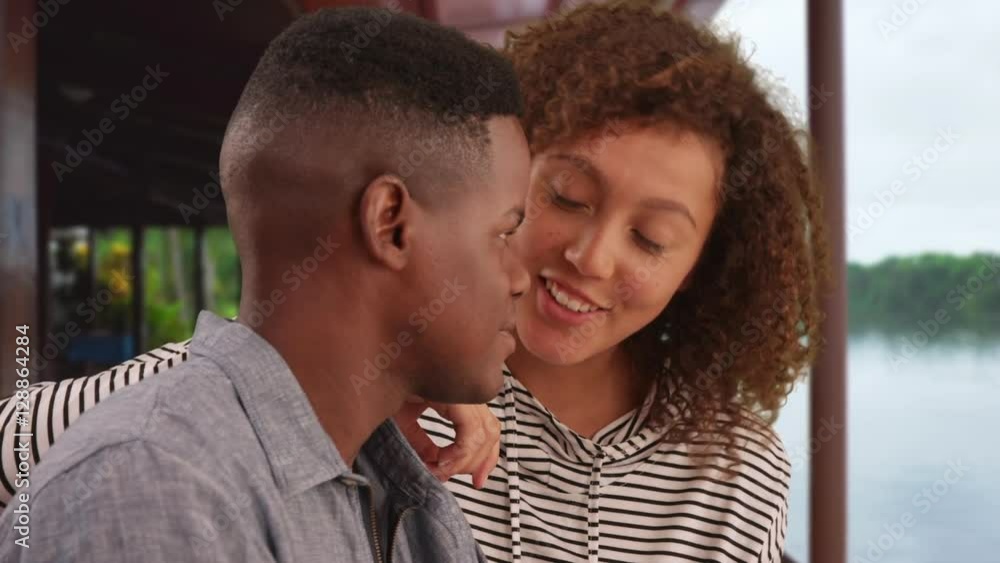 Millennial black man and woman talk next to the picturesque water. Young African American couple flirt in the tropics on vacation Millennial black man and woman talk next to the picturesque water. Young African American couple flirt in the tropics on vacation