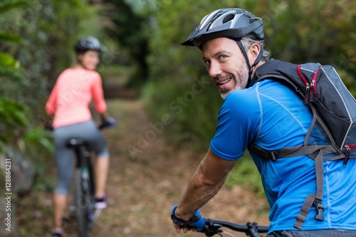 Athletic couple cycling in forest