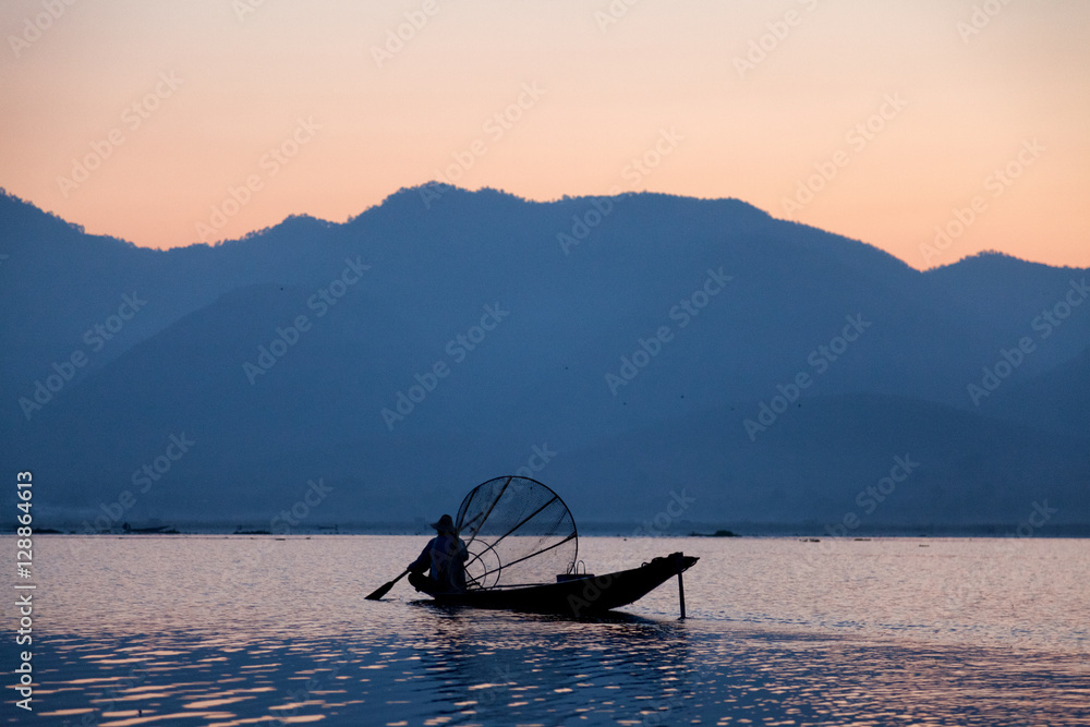 Naklejka premium Intha fisherman fishing at sunset in his typical canoe with fish