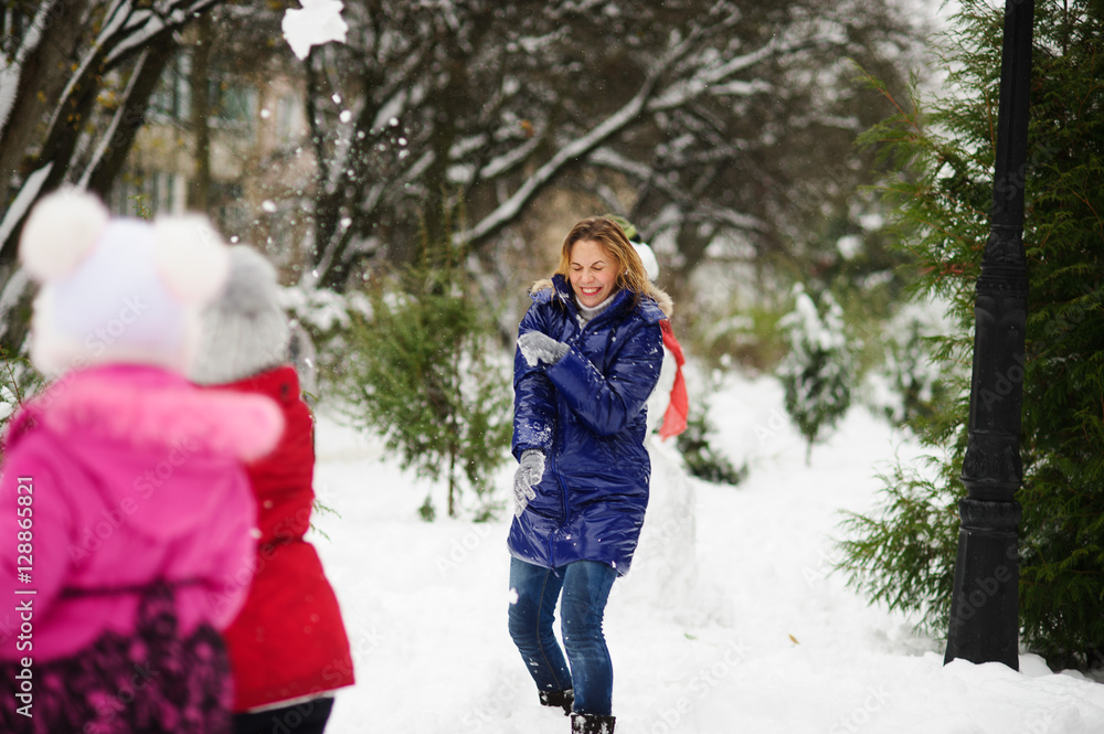 Fototapeta premium White Christmas. Girl plays with mother in snowballs in the winter park.
