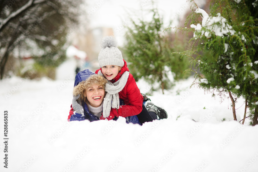 Young woman with daughter of school age lie having embraced on snow.