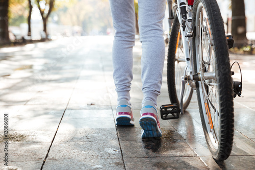 Cropped photo of woman walking with her bicycle in street