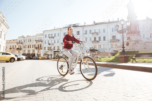 Young girl dressed in sweater walking with bicycle in city