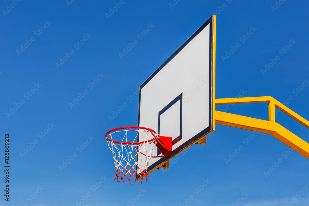 basketball board with red hoop on blue sky background