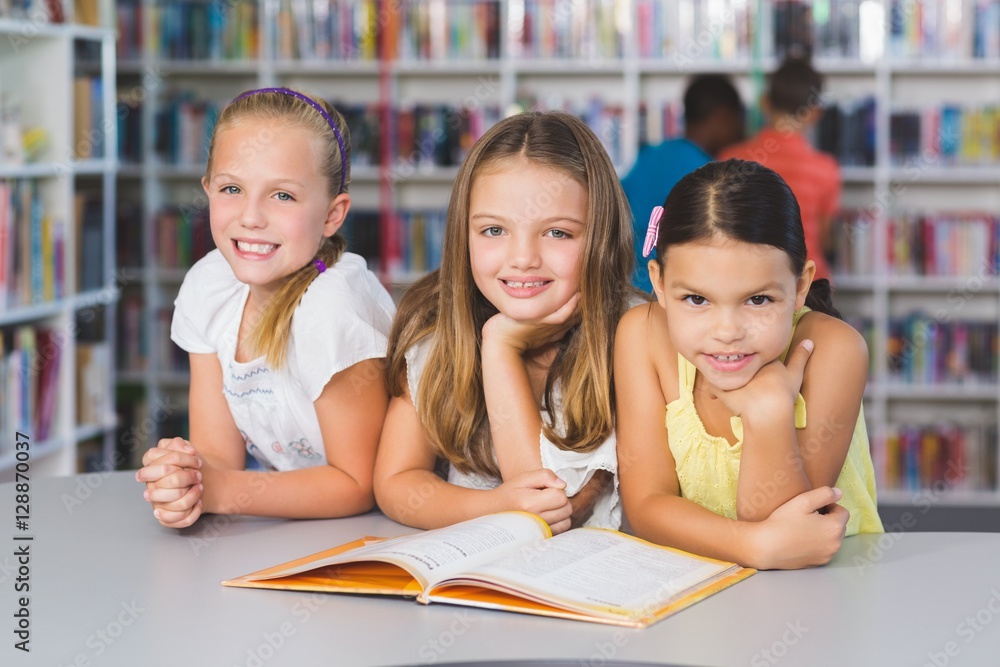 School kids reading book together in library School kids reading book together in library