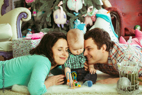 young and happy parents with their cute little boy lying near Ch
