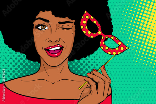 Pop art face. Young sexy african woman with carnival mask in her hand smiling and winking on dots background. Vector illustration in retro comic style. Holiday party invitation poster.
