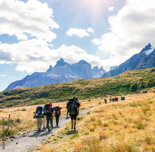 Group of travelers with backpacks walk along a trail towards a mountain ridge.Backpackers and hikers style. Concept of active leisure.