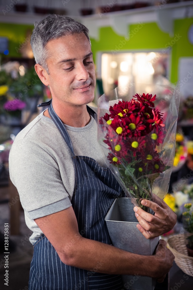 Fototapeta premium Male florist holding bunch of red sunflower in vase