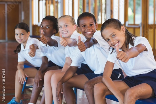 Fototapeta Portrait of school kids showing thumbs up in basketball court