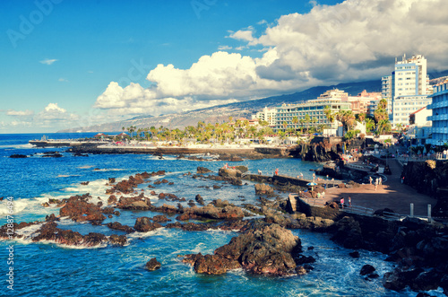 Coastal promenade in Puerto de la Cruz. Ocean bay and volcanic rocks in the water. Tenerife, Canary islands, Spain.