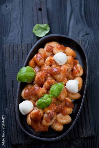 Potato gnocchi served with tomato sauce, cheese and basil leaves