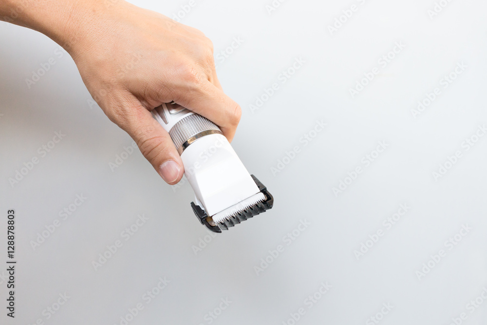 Hand holding hair clippers on grey background Hand holding hair clippers on grey background