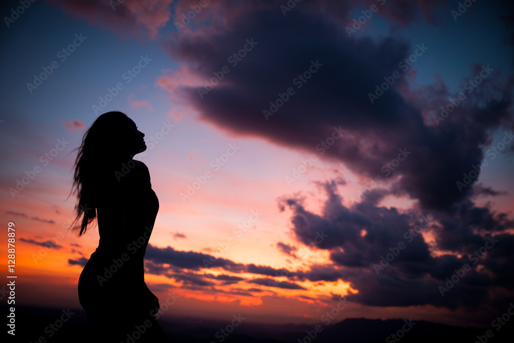 woman gesturing success - silhouette over evening sky
