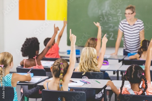 School kids raising hand in classroom photo