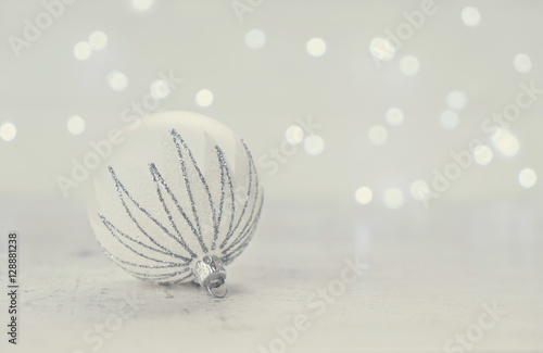 Christmas scene with one white and silver ball and christmas lights in background  retro toned