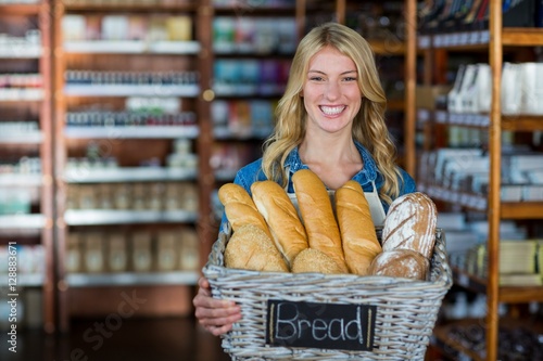 Smiling female staff holding a basket of breads