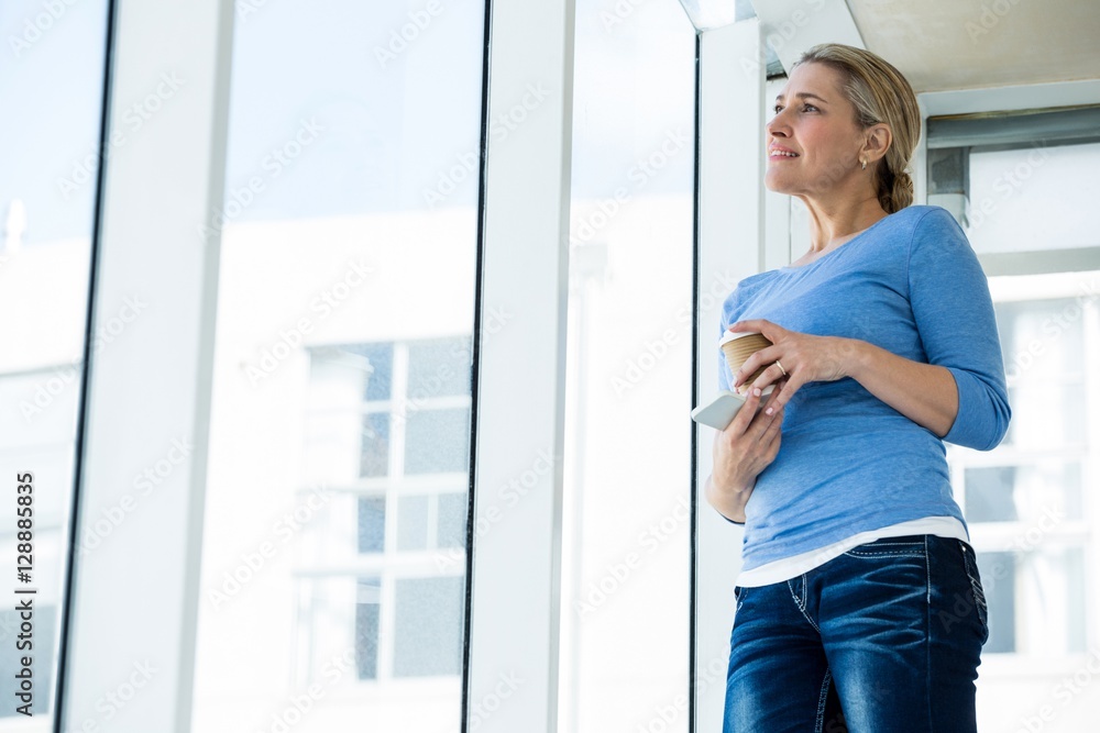 Thoughtful woman holding mobile phone and disposable cup Thoughtful woman holding mobile phone and disposable cup