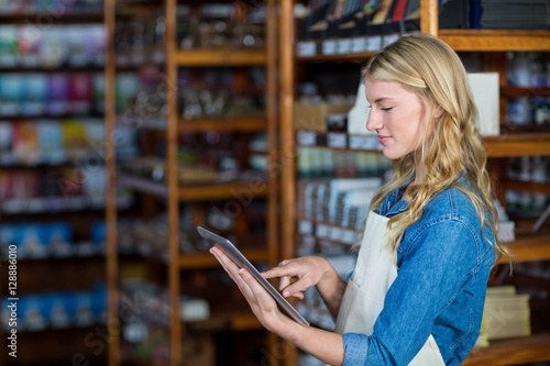 Female staff using digital tablet in supermarket