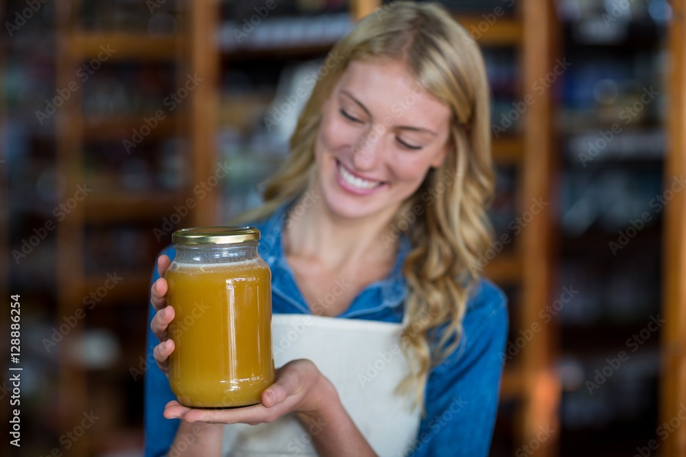 Female staff holding jar of honey in supermarket Female staff holding jar of honey in supermarket