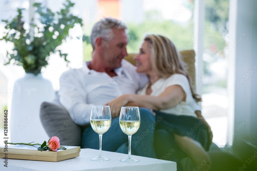 Romantic couple sitting on armchair with white wine and gift box Romantic couple sitting on armchair with white wine and gift box