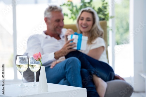 White wine on table with couple holding gift box